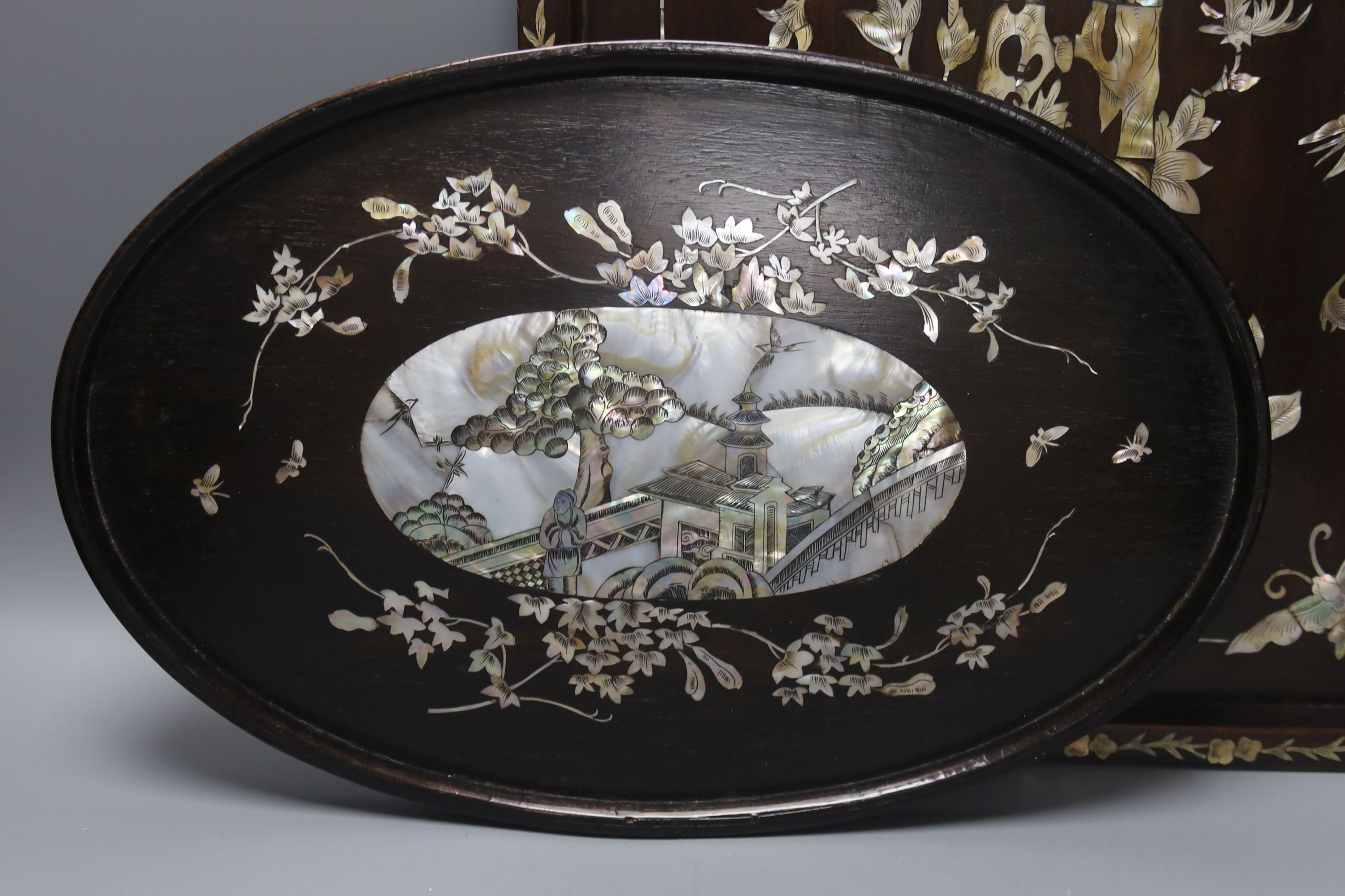 Two Chinese mother of pearl inlaid hongmu trays, the rectangular example with birds and insects amid flowers and the smaller oval example with a pavilion in a landscape within floral sprays 55x34cm